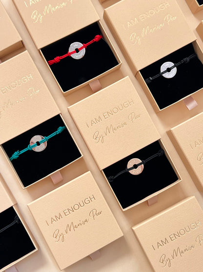 Jewelry boxes with bracelets inside, featuring 'I AM ENOUGH' by Mariana Peir on beige lids.